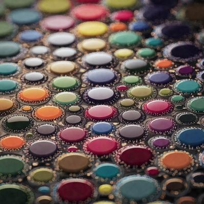The primary subject of the image is a close-up of a colorful, patterned surface. The setting is a colorful, multicolored background, which adds to the vibrant atmosphere of the scene. The visual style of the image is a combination of photo and digital art, creating a unique and eye-catching pattern. The dominant colors in the image are a mix of bright and bold hues, such as pink, blue, green, and yellow, which contribute to the lively and cheerful mood of the